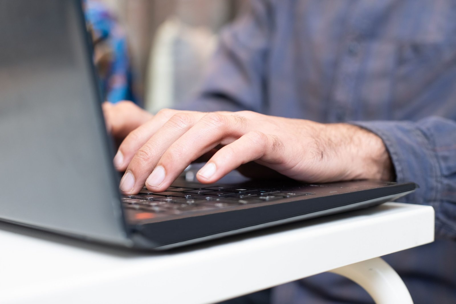 Close-up of hands typing on a laptop keyboard, focused and professional setting.